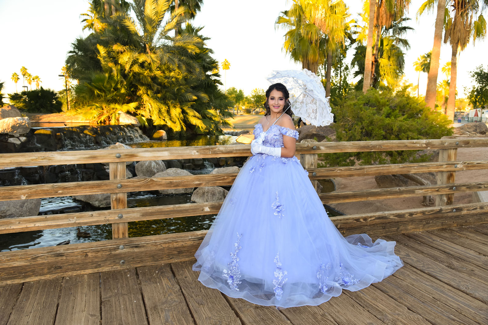 Quinceañera con un vestido lila y sombrilla blanca en un puente de Phoenix, Arizona.
